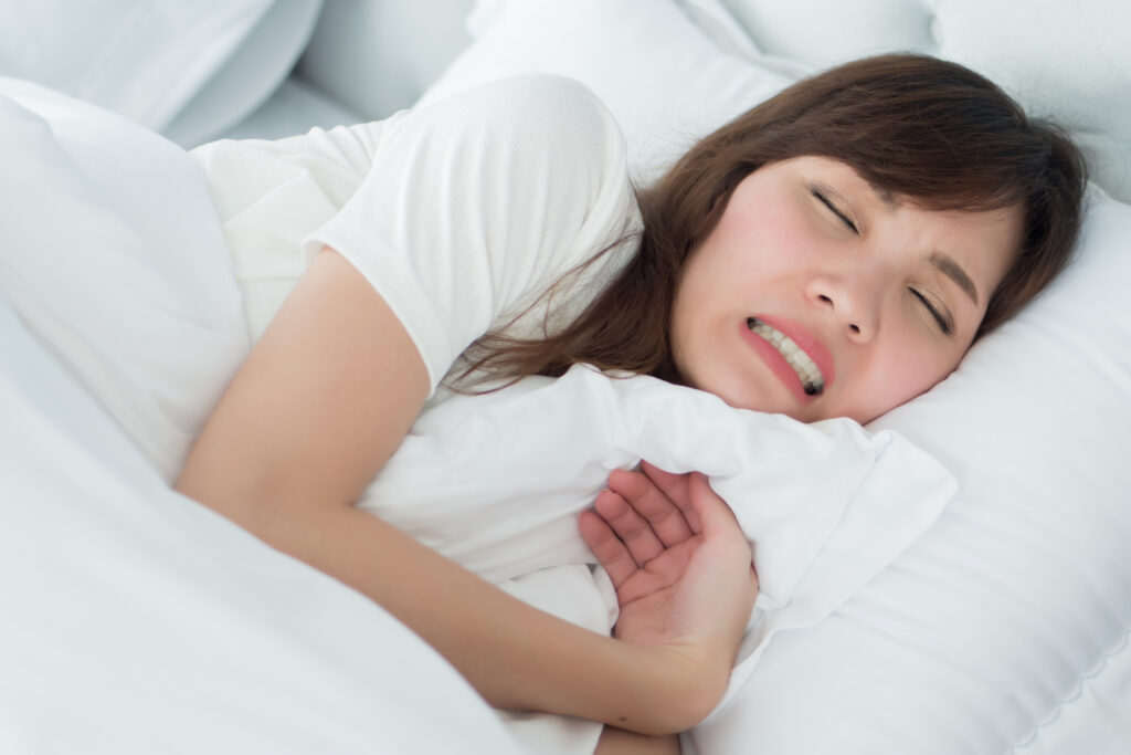 woman suffering from bruxism or teeth grinding in her sleep